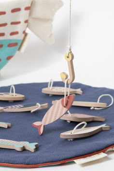 an ornament is hanging from a string on a blue cloth with wooden boats