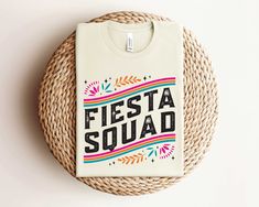 a white t - shirt that says fiesta squad on it sitting on top of a wicker basket