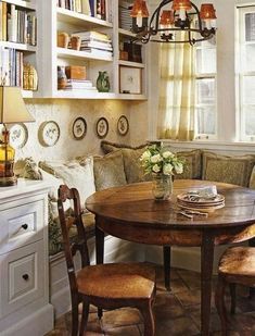 a dining room table with chairs around it and bookshelves on the wall behind it