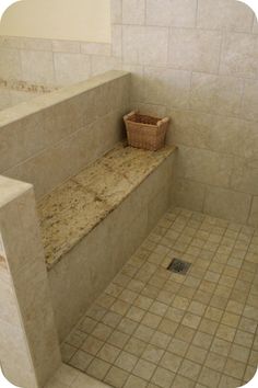 a tiled bathroom with a bench and basket on the counter next to tile flooring