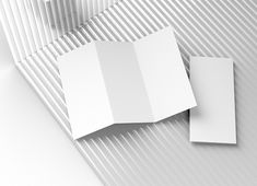 two folded white cards sitting next to each other on top of a striped wallpaper