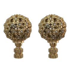 two gold colored vases with crystal stones on them, one is shaped like a ball and the other is made out of metal