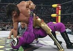 two wrestlers in purple wrestling outfits on the ground with one wrestler holding his leg up