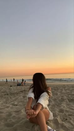 a woman sitting on top of a sandy beach