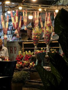 a man sitting at a table in front of a flower shop filled with lots of flowers