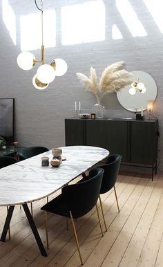 a dining room table and chairs in front of a white brick wall with round lights