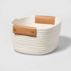 a white rope basket with leather handles