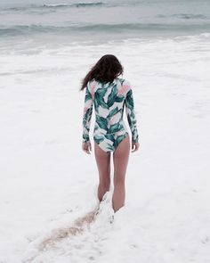 a woman in a bathing suit walking into the ocean