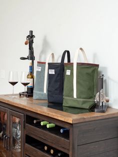 three wine bags sitting on top of a wooden table next to a glass of wine