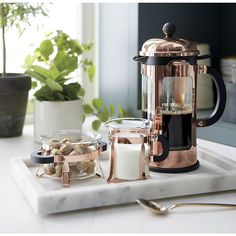 a coffee maker sitting on top of a counter next to a bowl of nuts and milk