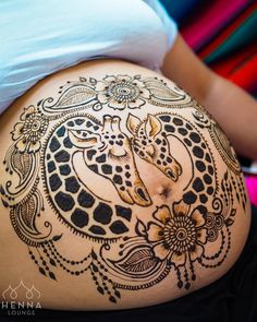 a pregnant belly with an intricate giraffe tattoo on it's side,