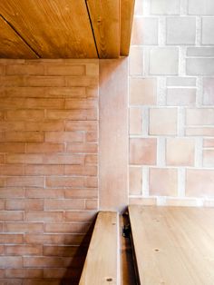 two wooden benches sitting next to each other in front of a brick wall and ceiling