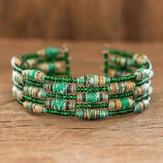 the green and gold bracelets are stacked on top of each other, with beads