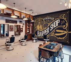 a barber shop with chairs and tables in front of a large sign on the wall