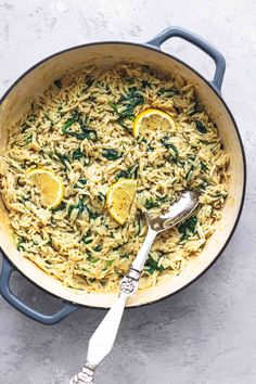 a pot filled with pasta and lemons on top of a white table next to a silver spoon