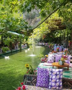 an outdoor seating area with colorful cushions and flowers on the tables next to the water