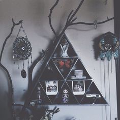 there is a triangle shaped shelf with pictures on it and other decorations hanging from the wall