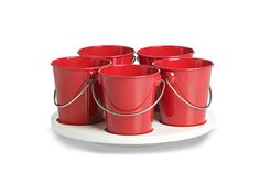 six red buckets sitting on top of a white plate with rope around the handles