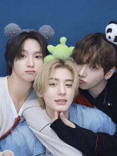 three young men laying next to each other on top of a blue wall with panda ears