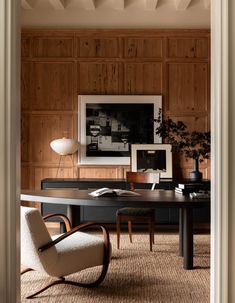 an office with wooden paneled walls and desk in the center, surrounded by chairs