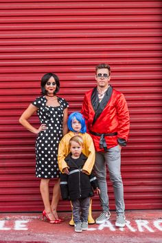 a man, woman and child standing in front of a red garage door with their arms around each other