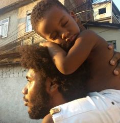 a man holding a small child in his arms while standing next to another man's head