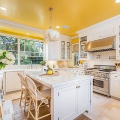 a large kitchen with white cabinets and yellow walls, along with an island in the middle