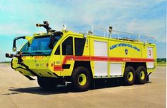 a large yellow fire truck parked on top of an airport tarmac with no one around it