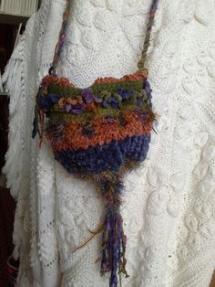 a white sweater with a multicolored purse hanging from it's back end