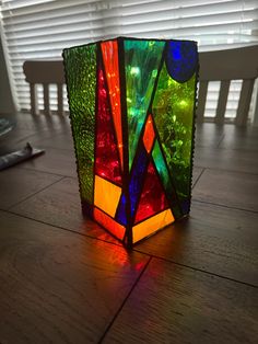 a multicolored lamp sitting on top of a wooden table next to a window