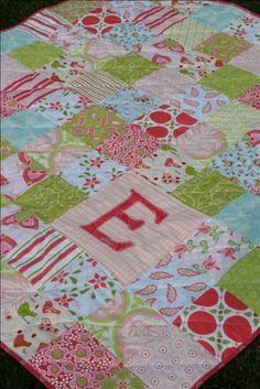 a patchwork quilt on the ground with letters and numbers in red, green, blue, and pink