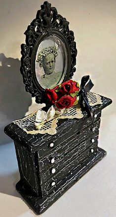 there is a small black box with a mirror on it that has roses in it