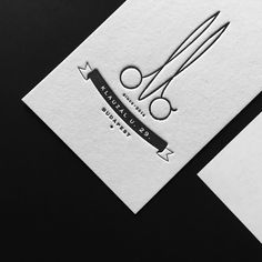 two business cards with scissors on them and one has a logo for the company's name