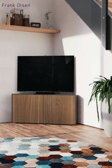 a flat screen tv sitting on top of a white cabinet next to a potted plant