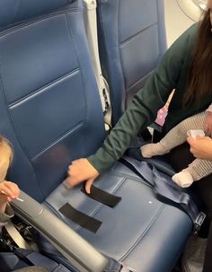 a woman holding a baby in her arms on an airplane seat with another child sitting next to her