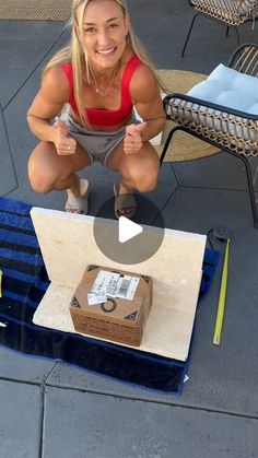 a woman kneeling down with a box on the ground next to her and an open laptop in front of her