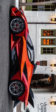 an orange and black car hanging from the side of a building