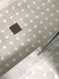 a shower stall with a drain in the middle and tile on the floor next to it