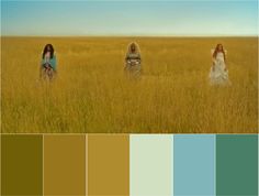 three women in long dresses walking through tall grass