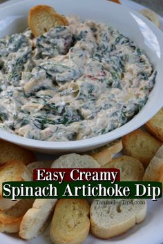 spinach artichoke dip in a white bowl surrounded by bread