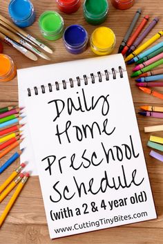 a spiral notebook with the words daily home preschool schedule written on it surrounded by crayons and markers