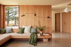 a living room filled with lots of furniture next to a large window and wooden paneled walls