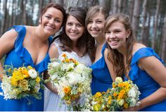 a group of women standing next to each other in front of trees and holding bouquets