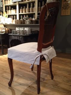 a wooden chair sitting on top of a hard wood floor next to a shelf filled with jars