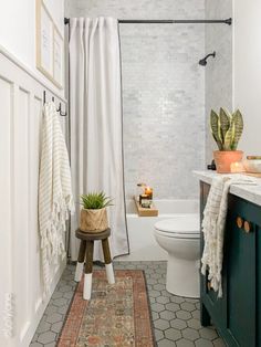 a bathroom with a rug, toilet and bathtub next to a shower curtain that has a succulent plant in it