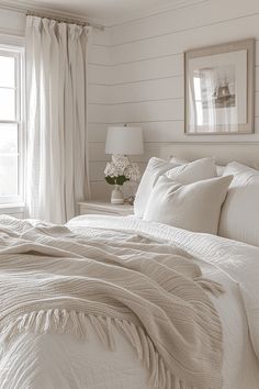 a bed with white linens and pillows in a bedroom next to two framed pictures on the wall