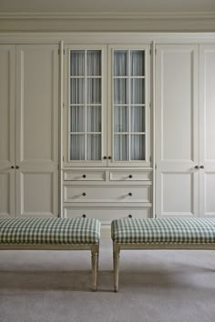 two checkered bench cushions in front of white built - in cabinets and cupboards