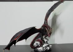 a statue of a dragon with its wings spread out on a table next to a white wall