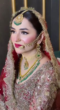 a woman in a bridal outfit with jewelry on her face and nose is posing for the camera