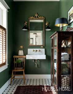 a bathroom with green walls and white tile on the floor, along with a wooden cabinet